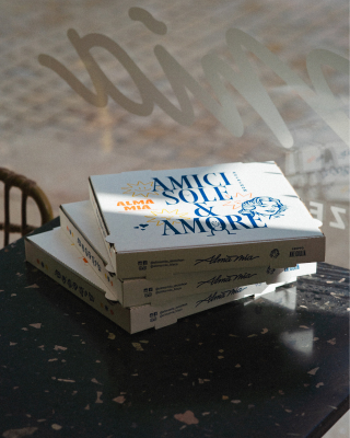 3 cartons à pizzas posés sur une table à Alma Mia Arcachon