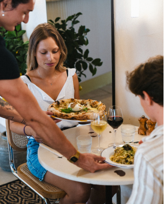 Table d'une pizzeria à Arcachon avec 2 personnes qui mangent un plat de pâte et une pizza